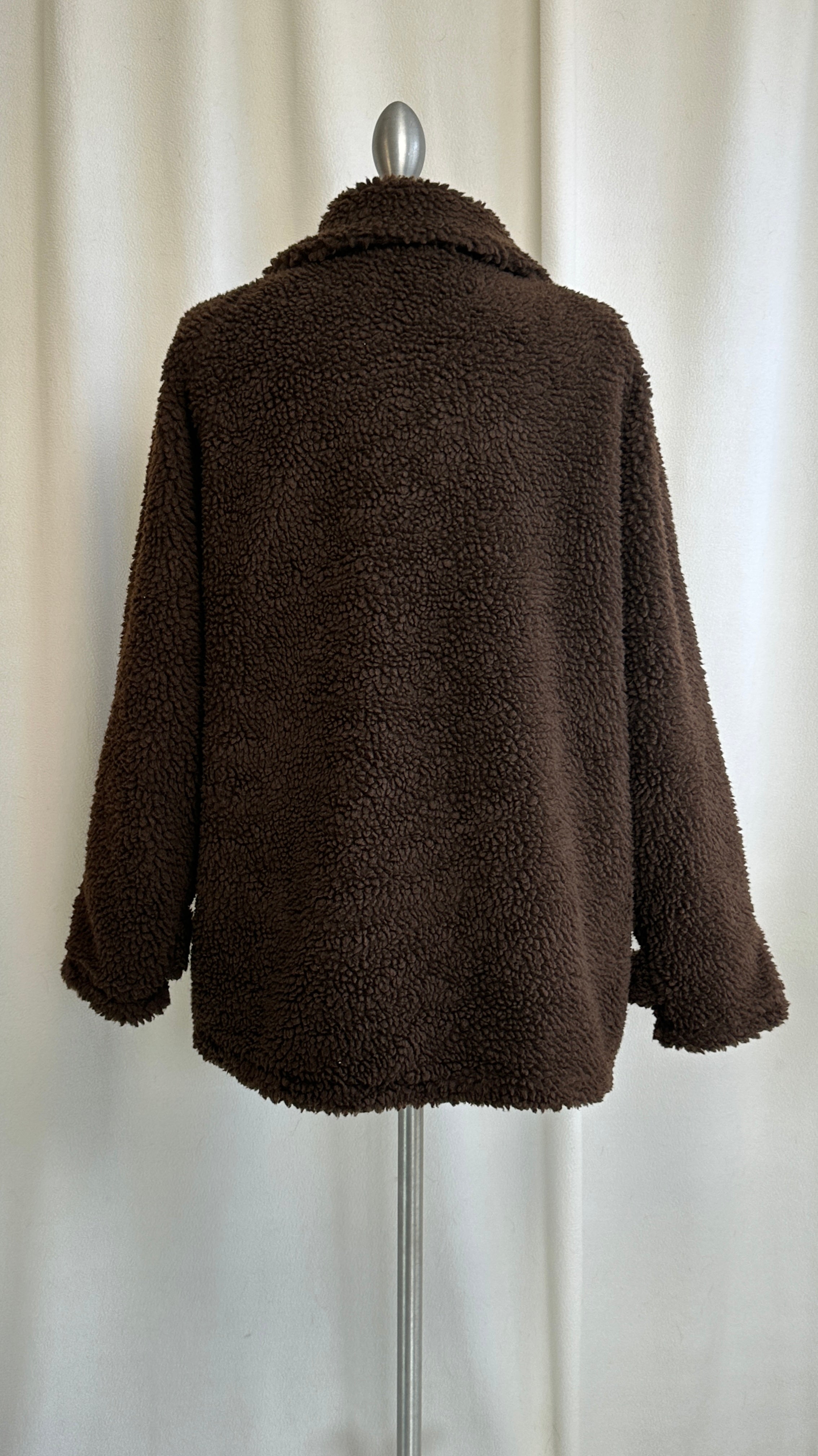 Brown teddy coat on a mannequin against a white curtain background