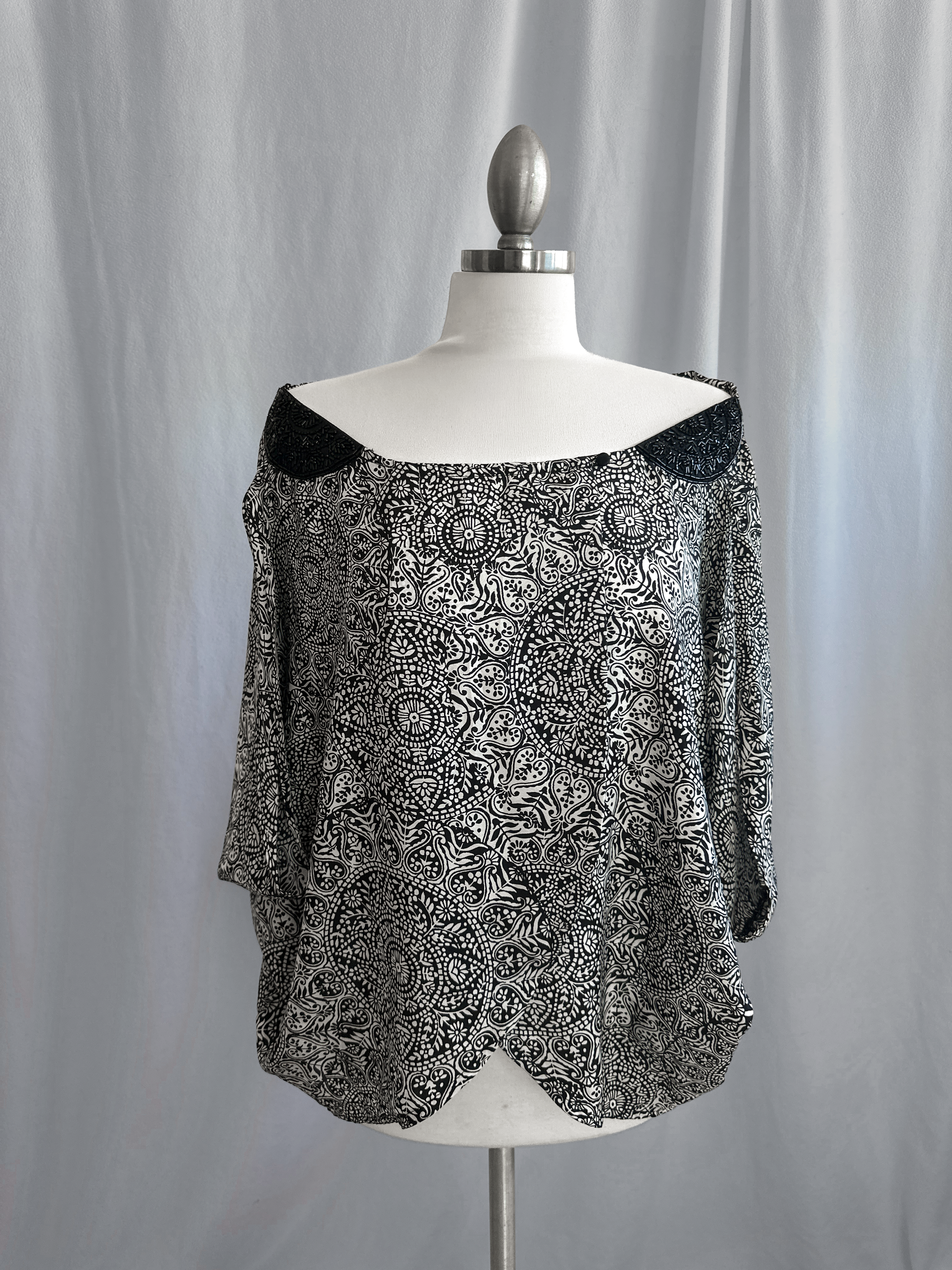 Black and white patterned blouse on a mannequin against a plain background