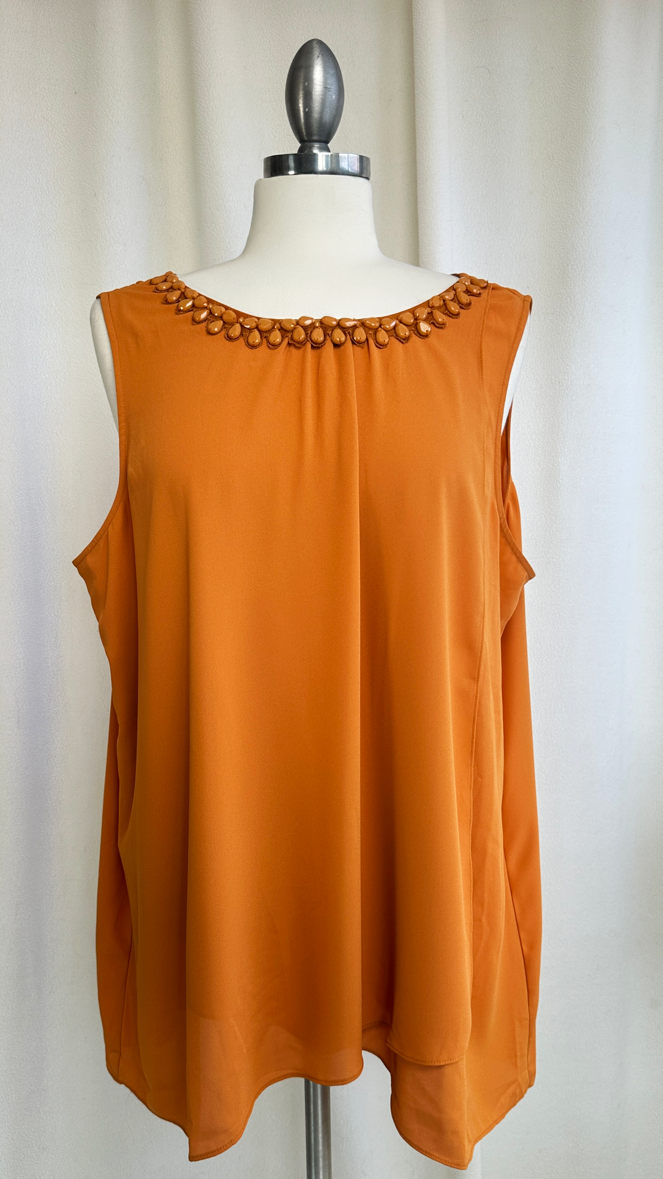 Orange sleeveless top with beaded neckline on a mannequin against a white background
