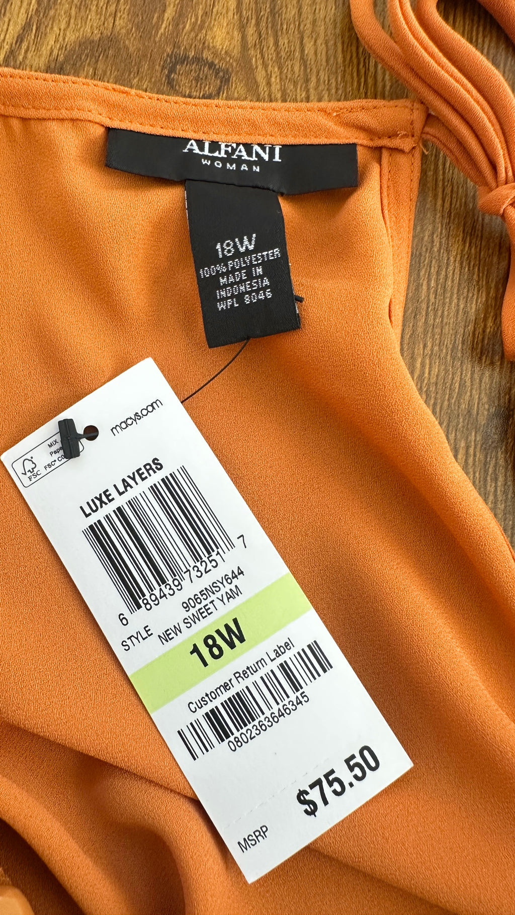 Orange garment with a label showing brand name and size on a wooden surface