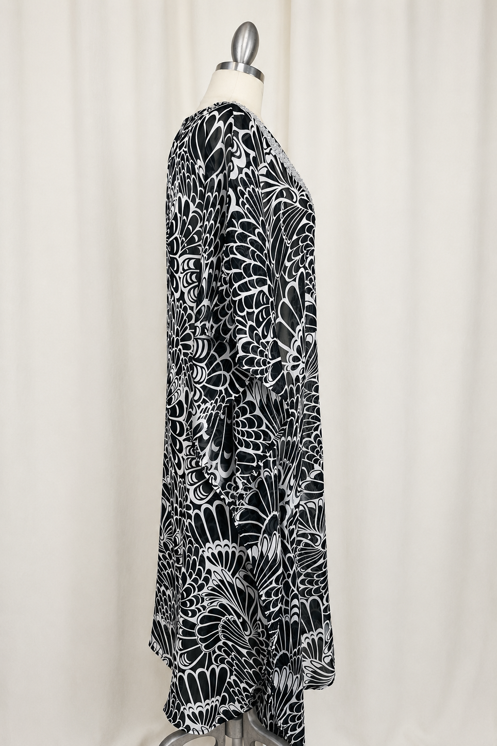 Black and white patterned dress on a mannequin against a white curtain background