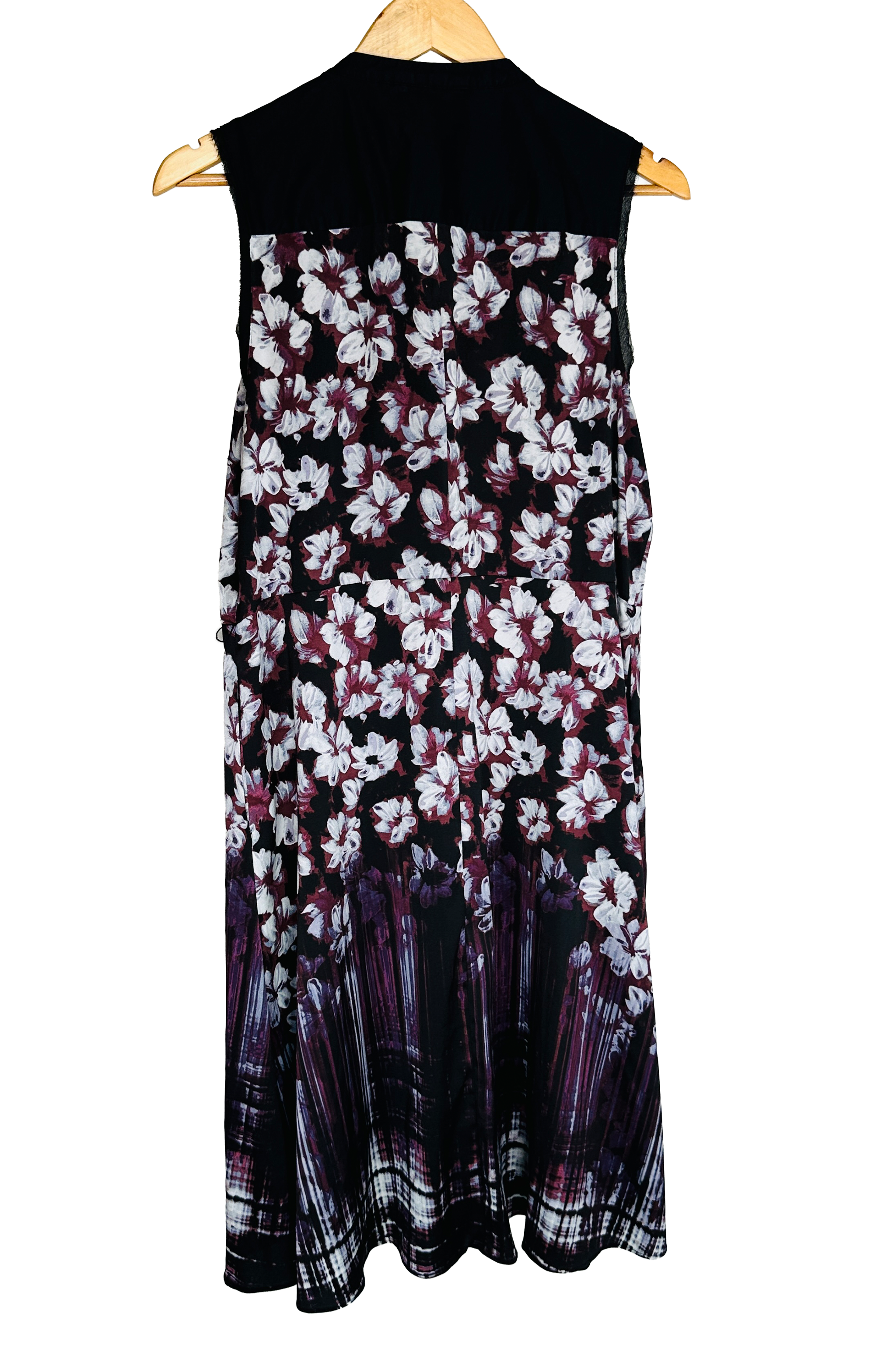 Same dress, back view on a wooden hanger. Solid black yoke across the upper back, sleeveless with sheer black side panels at the armholes. Continuous white and burgundy floral print breaking into a streaked vertical border at the hem.