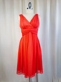 Orange dress on a mannequin against a white curtain background