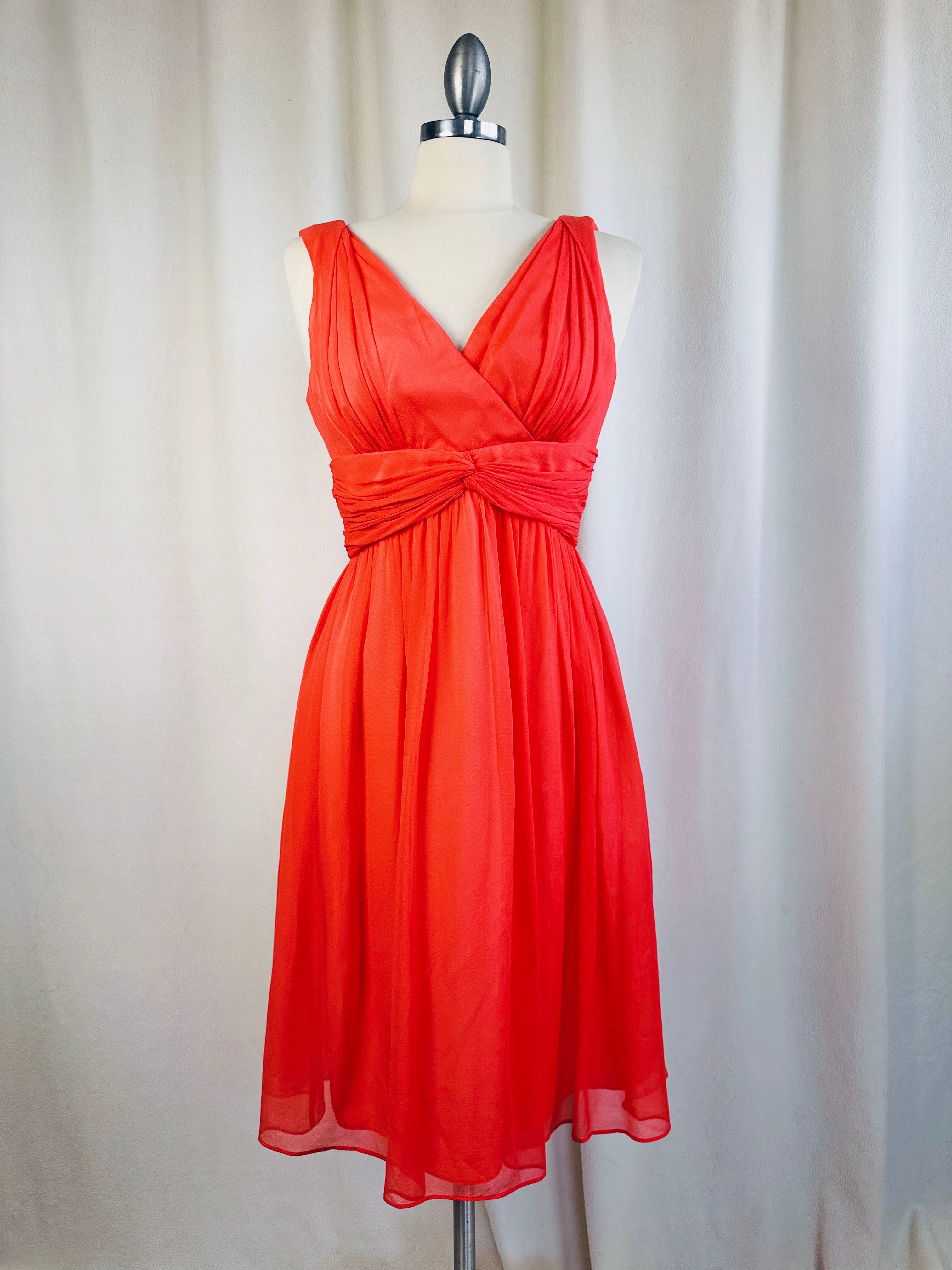 Orange dress on a mannequin against a white curtain background