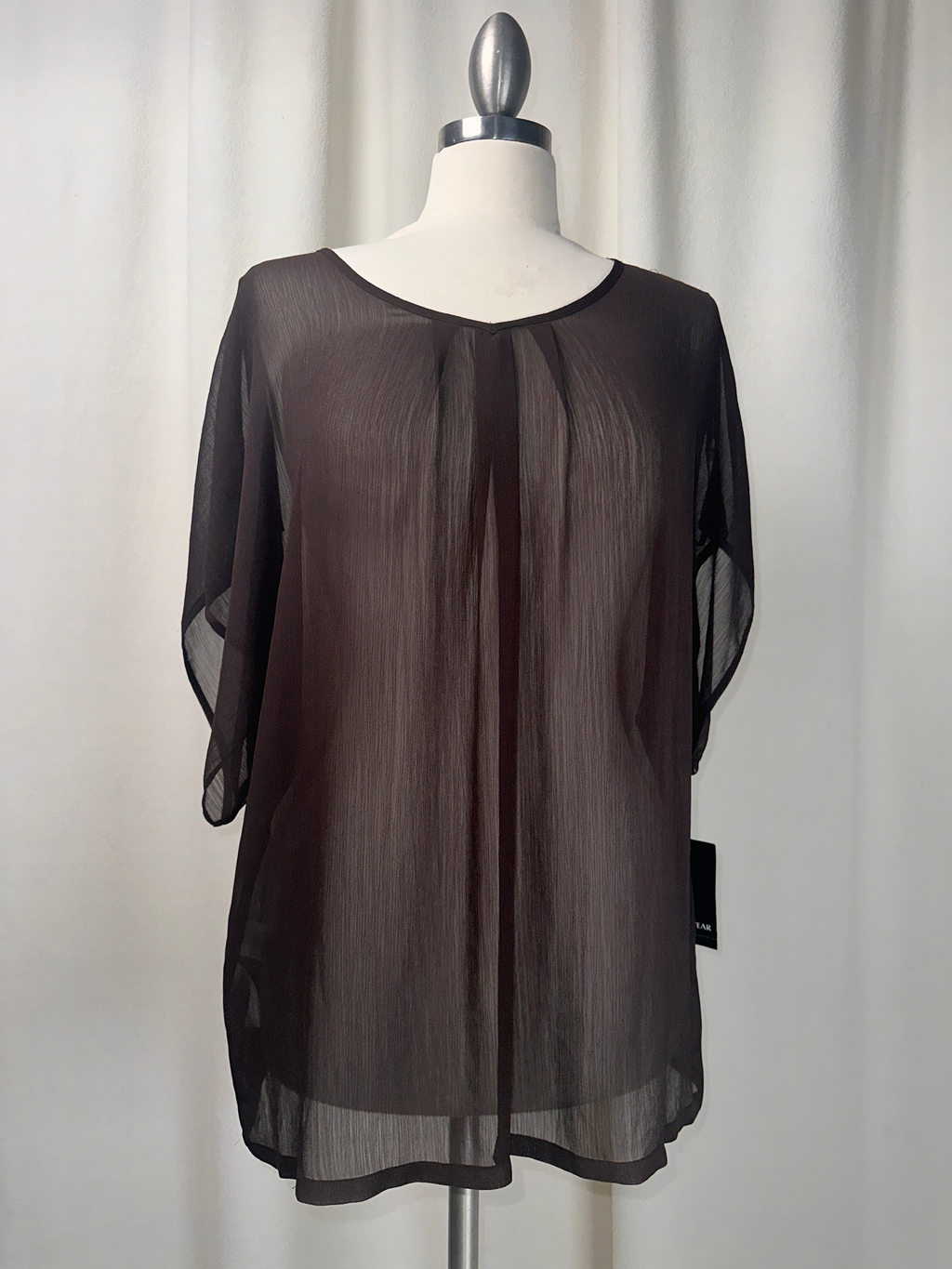 Black sheer blouse on a mannequin against a white background