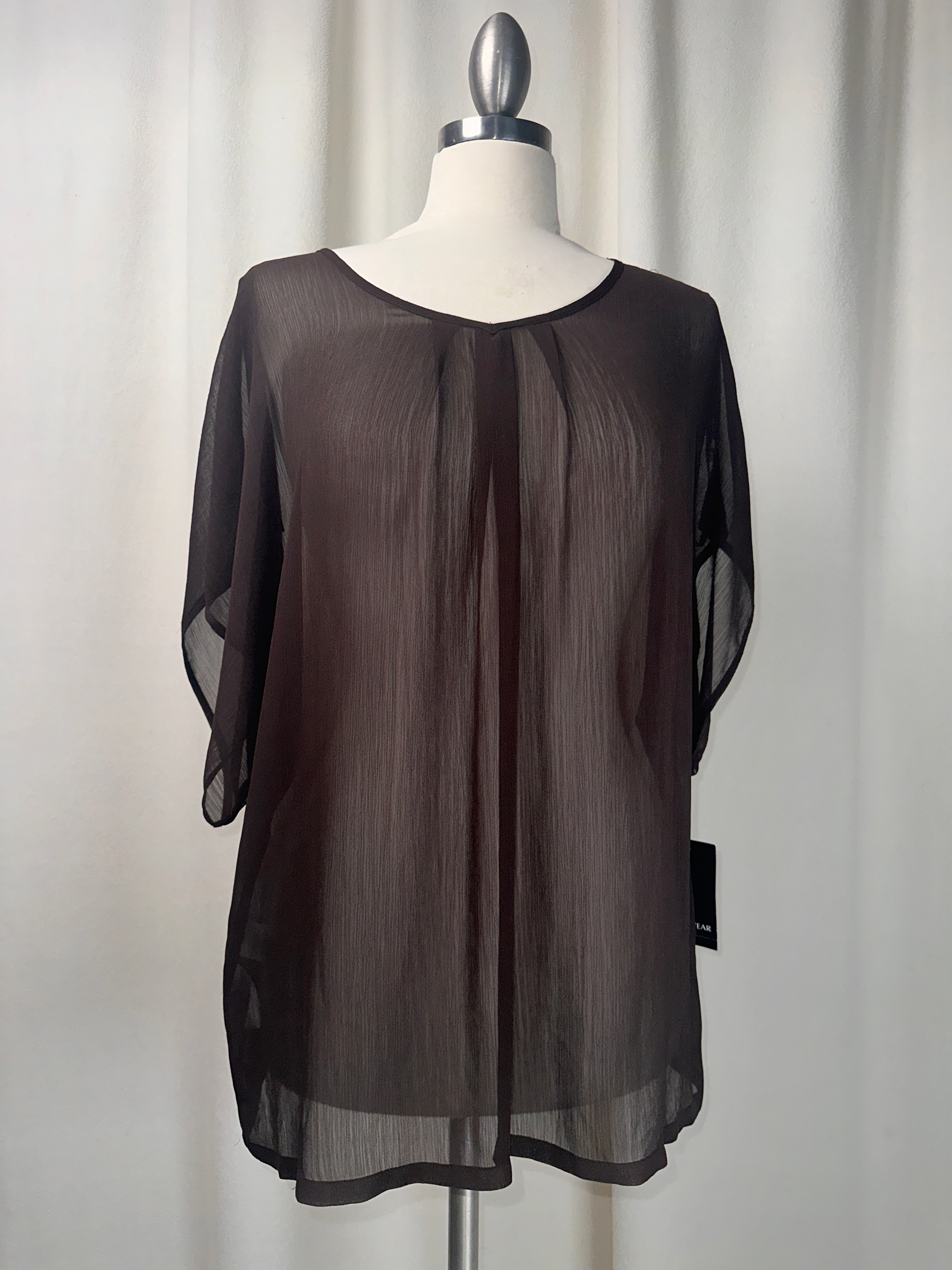 Black sheer blouse on a mannequin against a white background