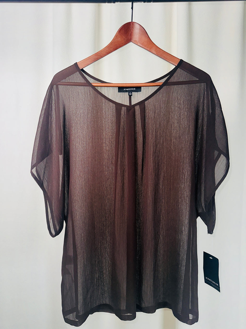 Sheer black top on a hanger against a white background
