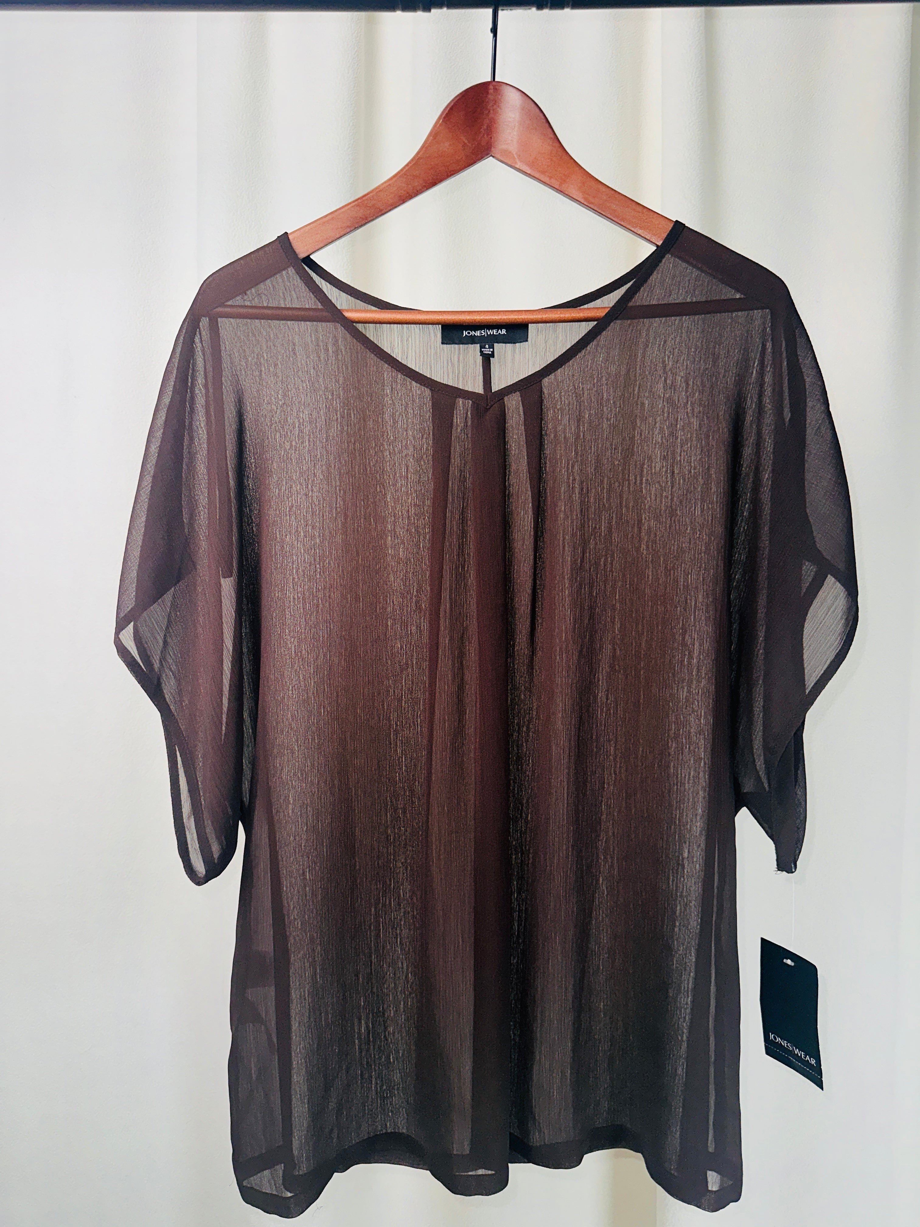 Sheer black top on a hanger against a white background