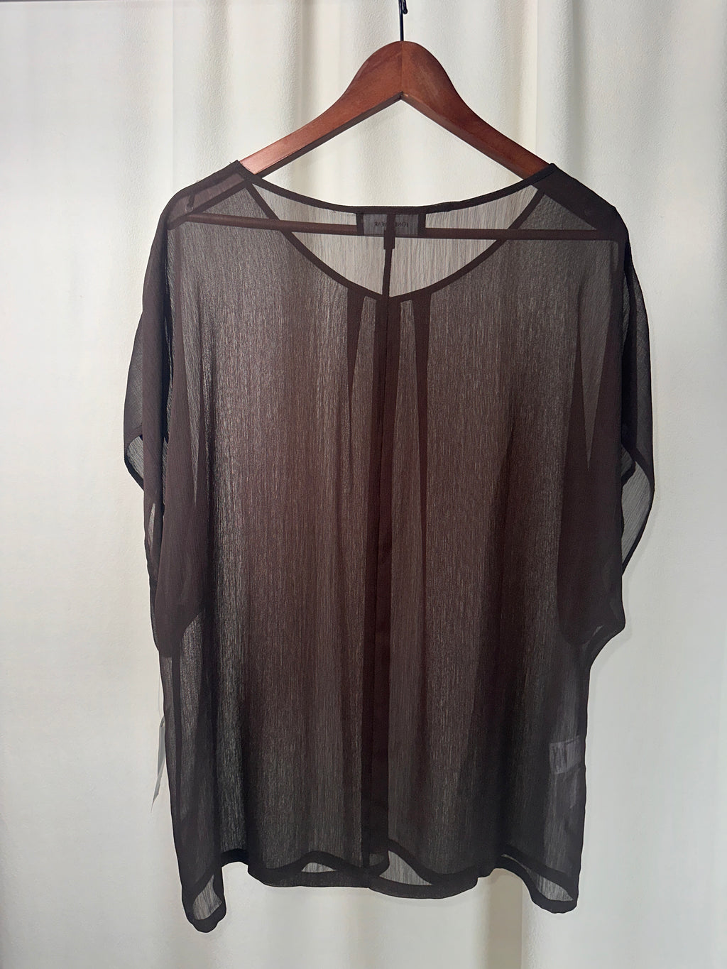 Black sheer blouse on a mannequin against a white background