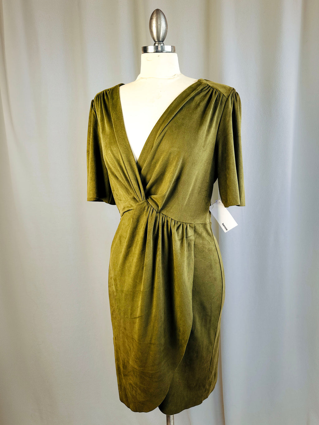 Green dress on a mannequin against a plain background