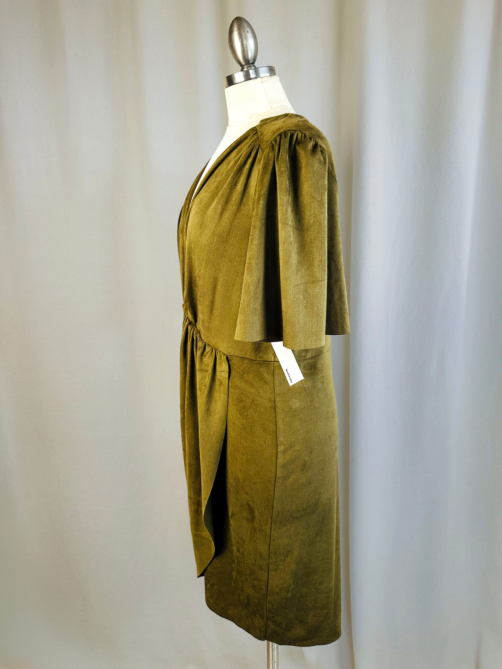 Green dress on a mannequin against a plain background