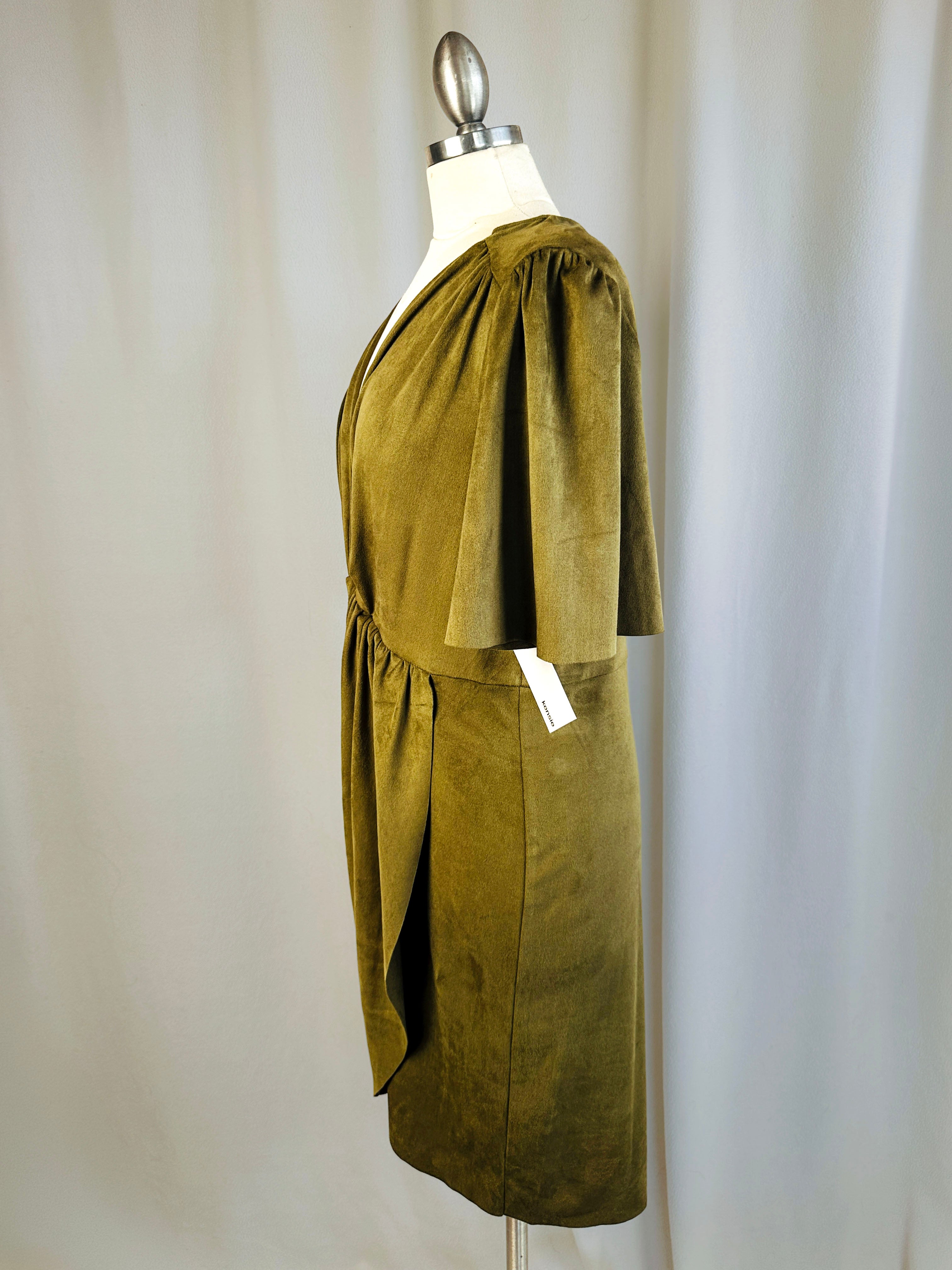 Green dress on a mannequin against a plain background