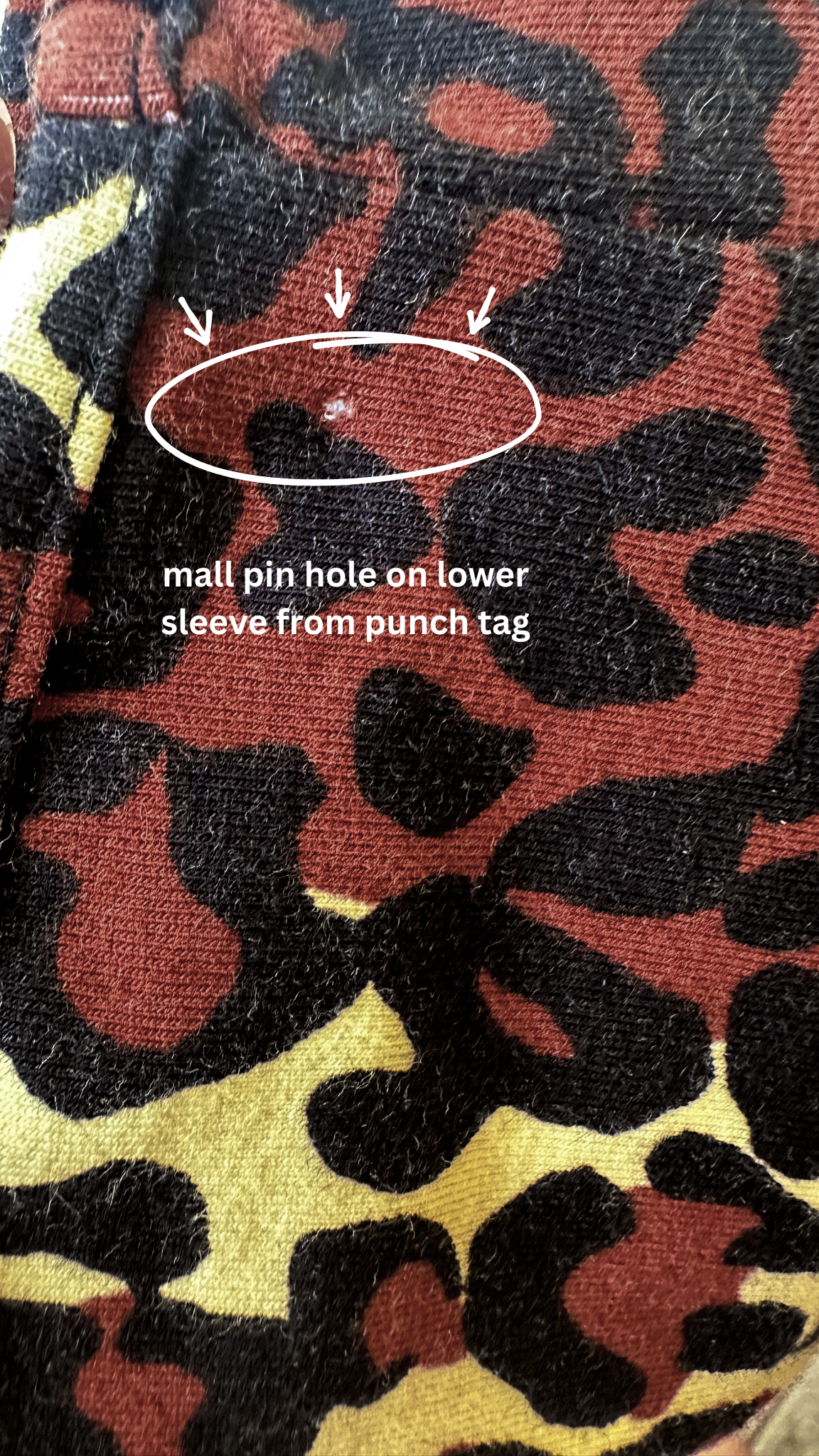Leopard print sleeve with a mall pin hole from a punch tag.