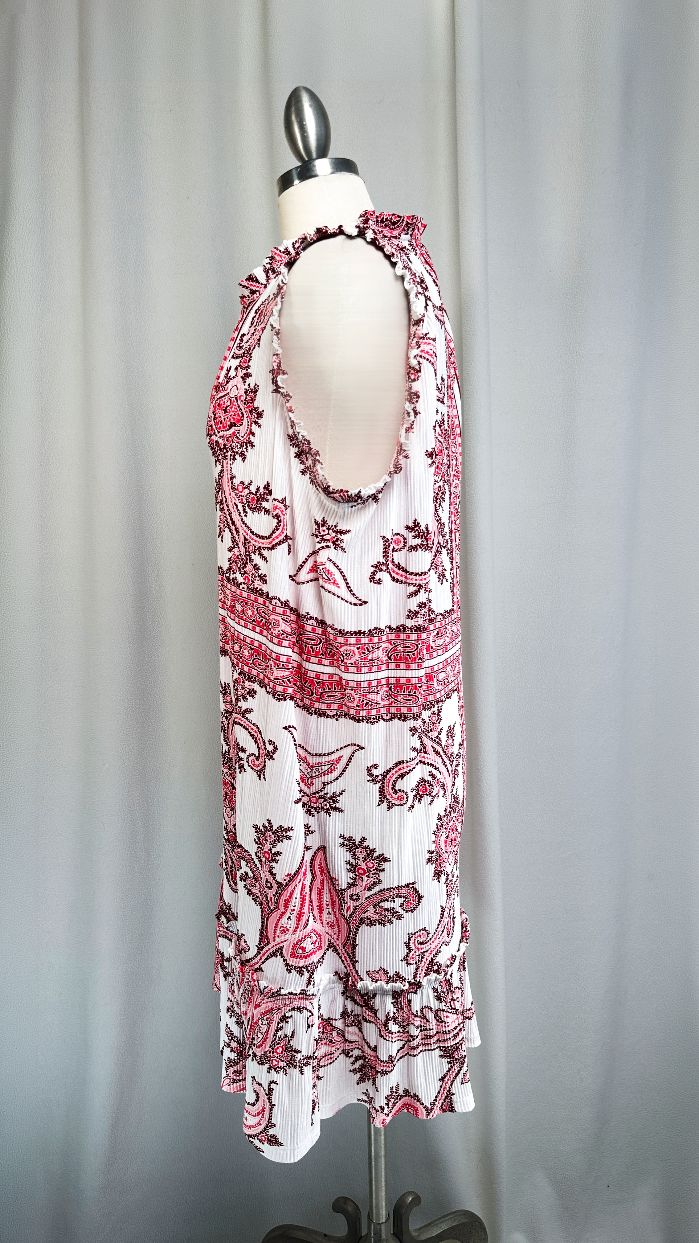 White dress with pink floral pattern on a mannequin against a gray background