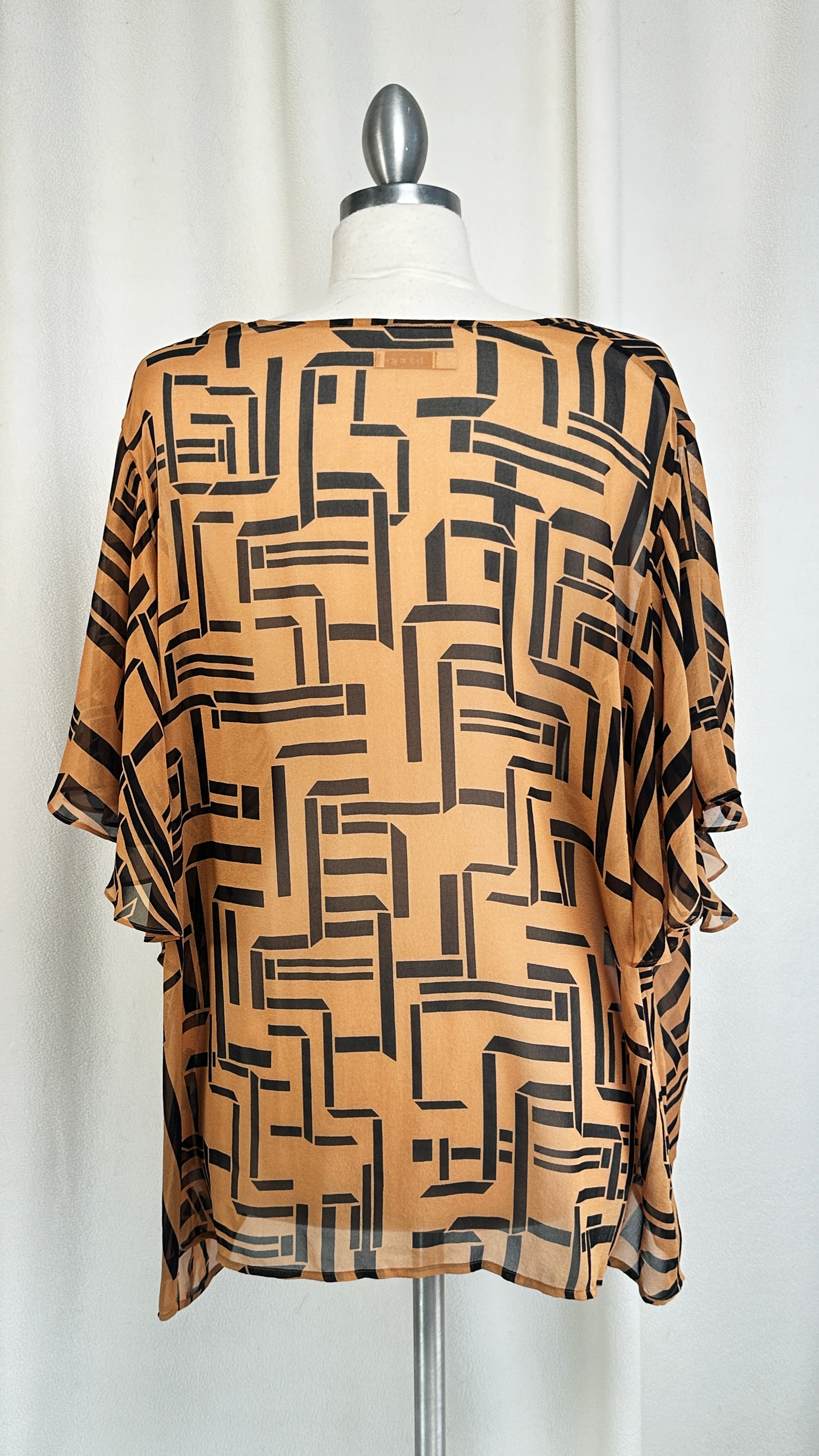 Brown and black patterned blouse on a mannequin against a white background