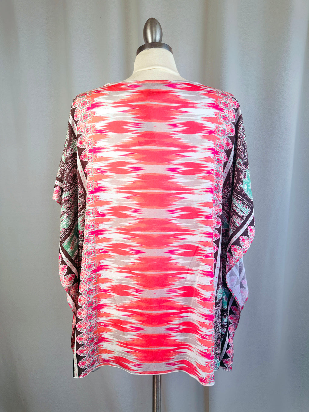 Colorful patterned shirt on a mannequin against a plain background