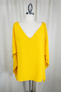 Yellow blouse on a mannequin against a plain background