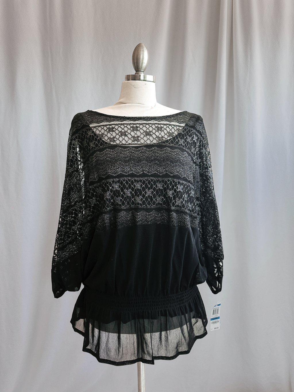 Black lace top on a mannequin against a plain background