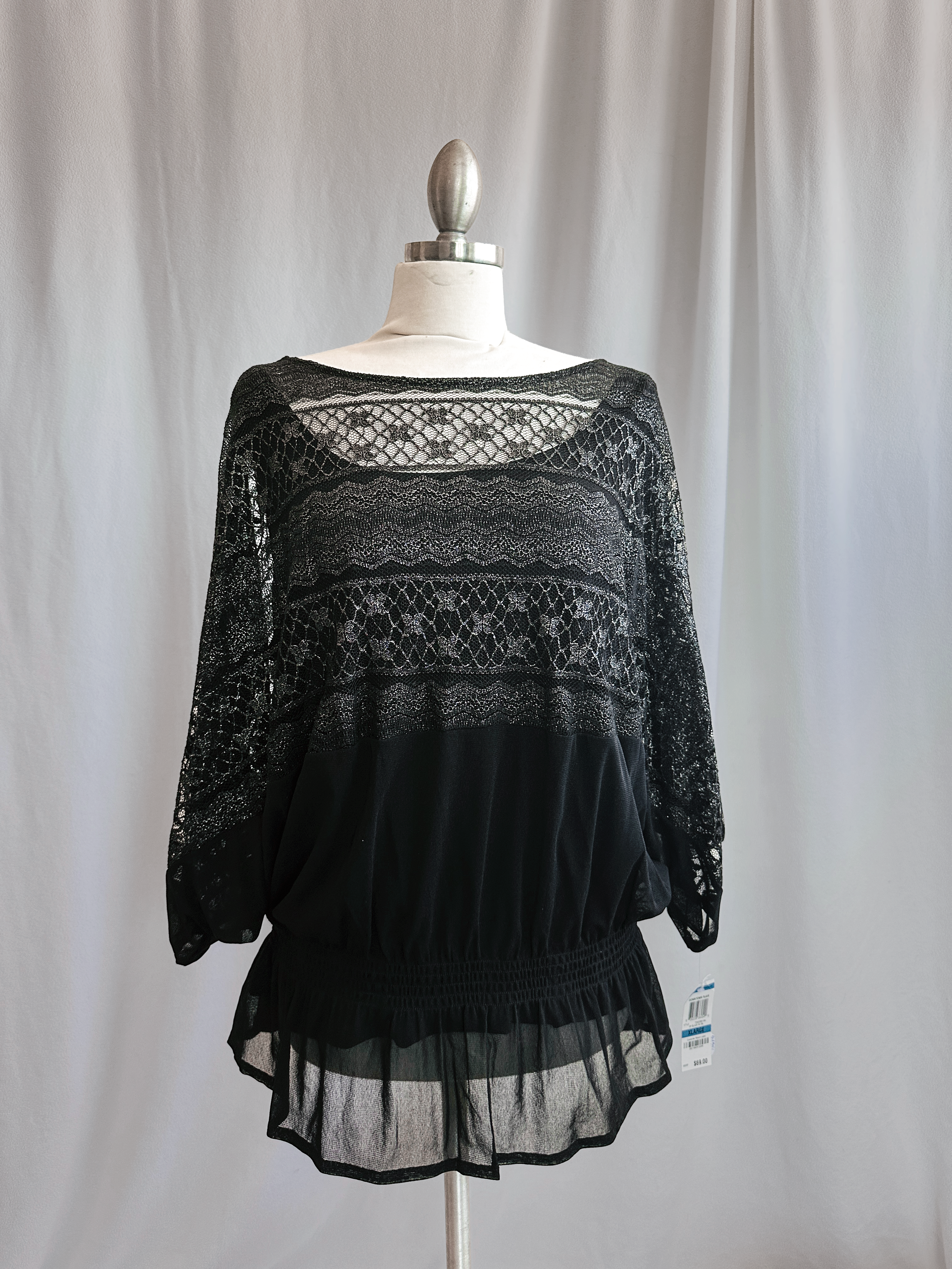 Black lace top on a mannequin against a plain background