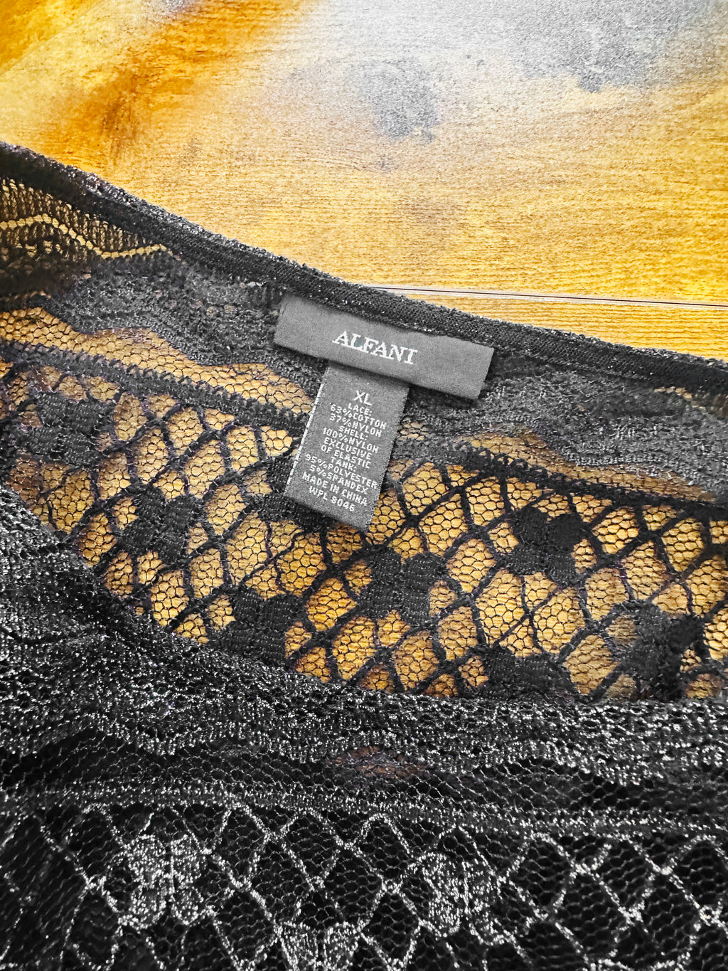 Close-up of a lace garment with an Alfani tag on a textured surface